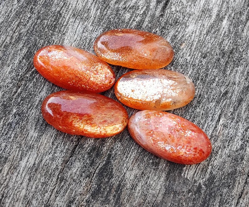 K&ouml;nnte beinhalten: Sechs glatte, ovale geschliffene Sunstone-Steine in Orange- und Goldt&ouml;nen mit einem schimmernden, irisierenden Finish.