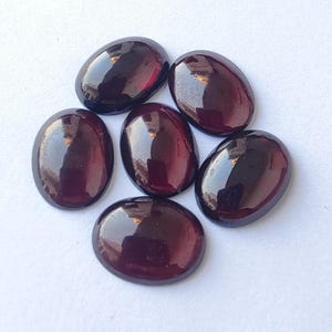 Puede incluir: Seis piedras preciosas ovaladas de color rojo oscuro con un acabado brillante.