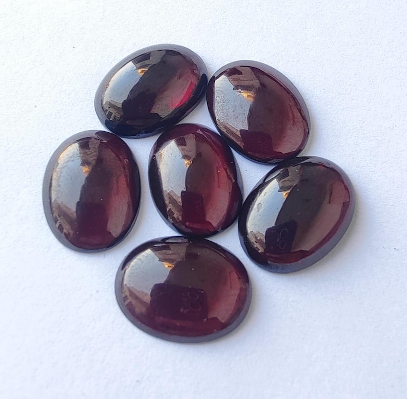 Puede incluir: Seis piedras preciosas ovaladas de color rojo oscuro con un acabado brillante.