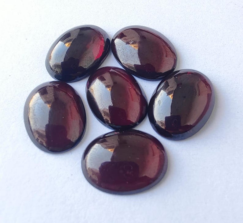 Puede incluir: Seis piedras preciosas ovaladas de color p&uacute;rpura intenso y rico. Las piedras son lisas y pulidas, con un acabado brillante.