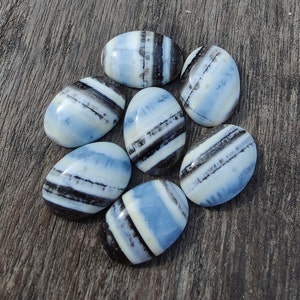 May include: Seven oval-shaped, polished stones with a blue and white banded pattern. The stones have a smooth, glossy finish.
