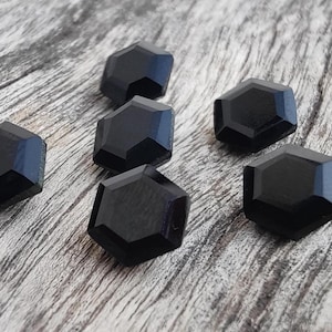 May include: Six black hexagonal shaped glass beads. The beads are faceted and have a glossy finish.