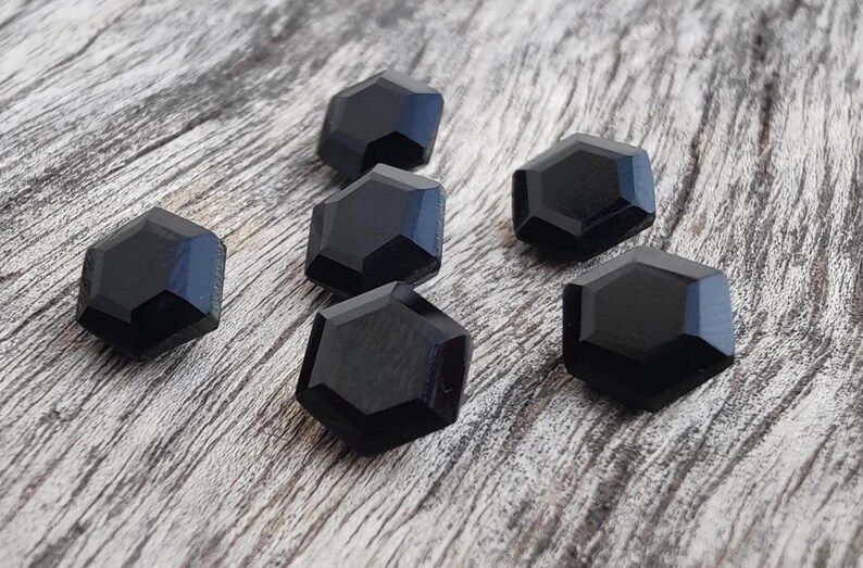 May include: Six black hexagonal shaped glass beads. The beads are faceted and have a glossy finish.