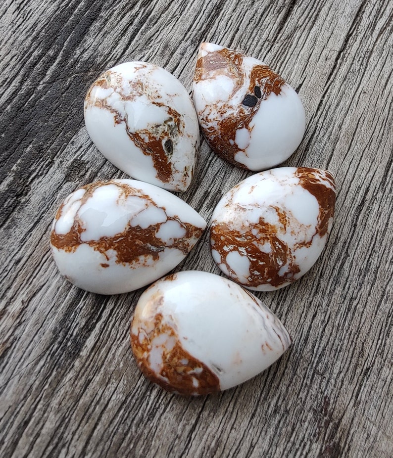 Puede incluir: Cinco cabujones en forma de l&aacute;grima de color blanco y marr&oacute;n con un patr&oacute;n de m&aacute;rmol.
