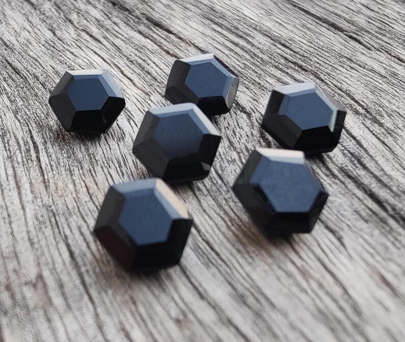 May include: Six black hexagonal-shaped buttons with a glossy finish.