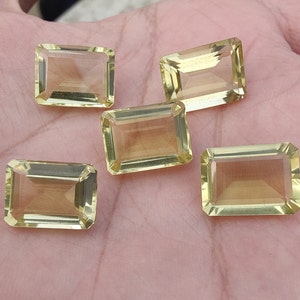 Puede incluir: Cinco cabujones rectangulares de piedra preciosa amarilla. Las piedras preciosas son facetadas y tienen una apariencia translúcida.