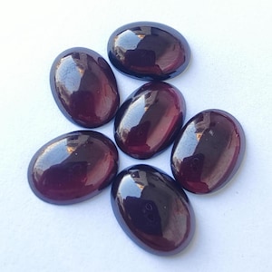 Puede incluir: Seis piedras preciosas ovaladas de color p&uacute;rpura oscuro con un acabado brillante.