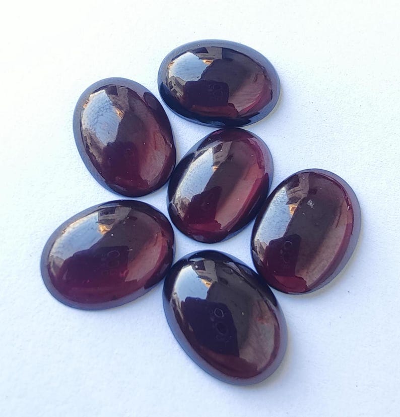 Puede incluir: Seis piedras preciosas ovaladas de color p&uacute;rpura oscuro con un acabado brillante.