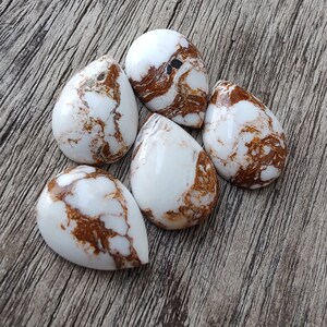Puede incluir: Cinco cabujones en forma de l&aacute;grima de color blanco y marr&oacute;n con un patr&oacute;n de m&aacute;rmol.