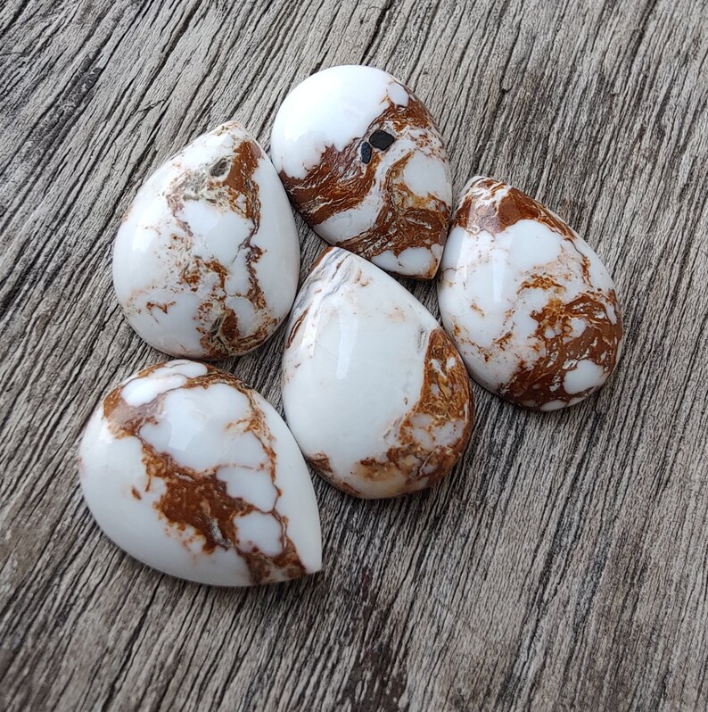Puede incluir: Cinco cabujones en forma de l&aacute;grima de color blanco y marr&oacute;n con un patr&oacute;n de m&aacute;rmol.