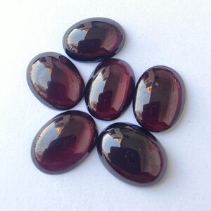 Puede incluir: Seis piedras preciosas ovaladas de color p&uacute;rpura oscuro con un acabado brillante. Las piedras est&aacute;n dispuestas en un racimo.
