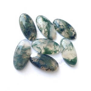 Puede incluir: Siete cabujones ovalados de ágata musgosa en tonos de verde, blanco y gris. Los cabujones son lisos y pulidos, con una variedad de patrones y texturas.
