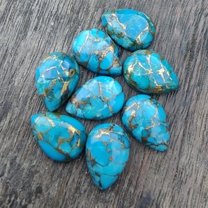 May include: Nine teardrop-shaped turquoise cabochons with gold flecks. The stones are a vibrant blue with a marbled pattern.