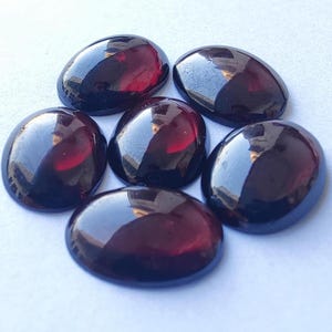 May include: Six oval-shaped, dark red gemstones with a high gloss finish.