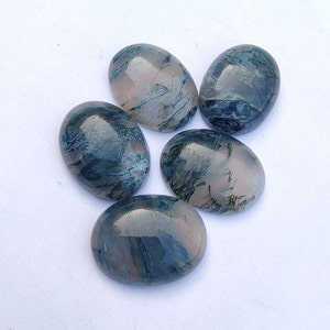 May include: Five oval-shaped agate cabochons with a blue and white dendritic pattern. The cabochons are smooth and polished.