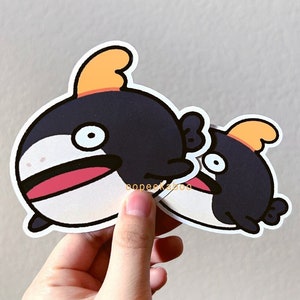 May include: Two black and white cartoon fish stickers with orange fins. The larger fish has a pink mouth and a surprised expression. The smaller fish is looking to the left.