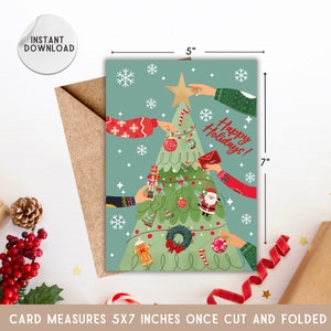 May include: A Christmas card featuring a green Christmas tree with a star on top. The tree is decorated with ornaments, candy canes, and a gingerbread man. There are multiple hands reaching towards the tree, holding ornaments and decorations. The card is 5 inches wide and 7 inches tall. The text on the card reads "Happy Holidays!"