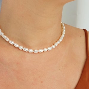 May include: A simple pearl necklace with a delicate chain and small, white pearls.