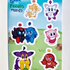 May include: A sheet of stickers featuring cartoon characters from "Sonic and Friends." The stickers include various colorful characters in different poses, set against a green background with pixelated elements. The top left corner has the text "Sonic and Friends."