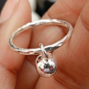 Puede incluir: Un anillo de plata con textura martillada y un colgante de bola.