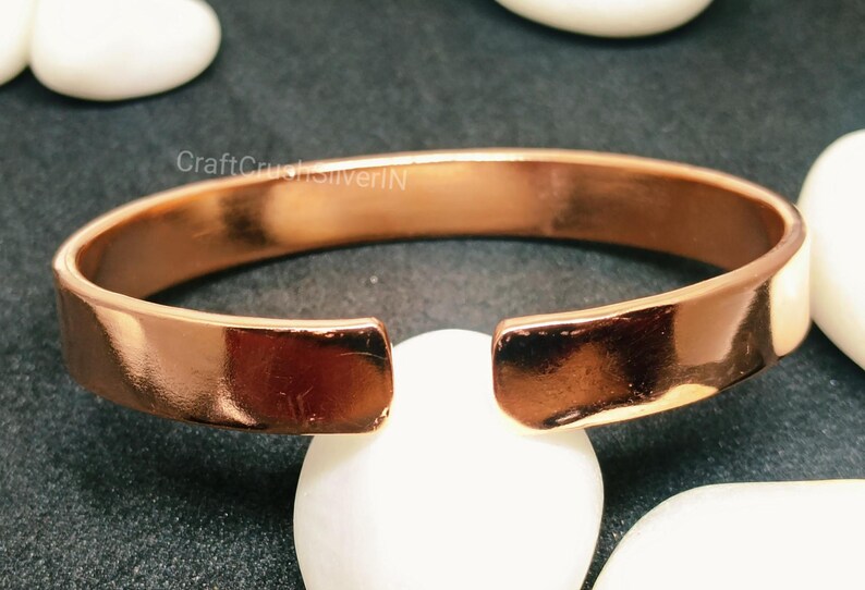 Peut inclure: Un bracelet jonc en cuivre avec une finition lisse et brillante. Le bracelet est ouvert aux deux extr&eacute;mit&eacute;s et pr&eacute;sente une l&eacute;g&egrave;re courbure.
