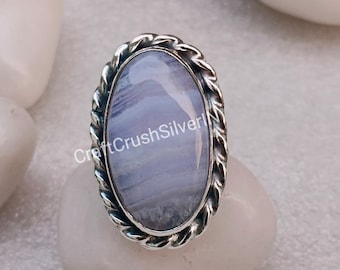 Könnte beinhalten: Ein ovaler Ring mit einem glatten, hellblauen, gebänderten Edelstein, der in einen polierten Silberrahmen mit einer gedrehten, seilartigen Umrandung gefasst ist. Der Text CraftCrushSilver ist in der Mitte des glänzenden Steins zu sehen.