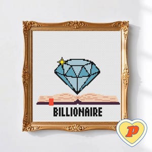 May include: Cross-stitch artwork in a gold ornate frame. The design shows a pixelated blue diamond above an open book with the word "BILLIONAIRE" in black block letters. A yellow heart-shaped sticker with a red "P" is in the lower right corner.