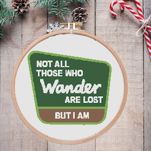 May include: A green and brown sign with the text "Not all those who wander are lost, but I am".