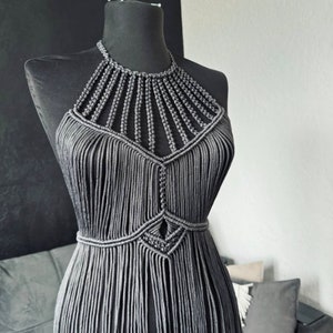 May include: A grey macrame halter top with a geometric design. The top is made of thin cords and has a fringe detail.