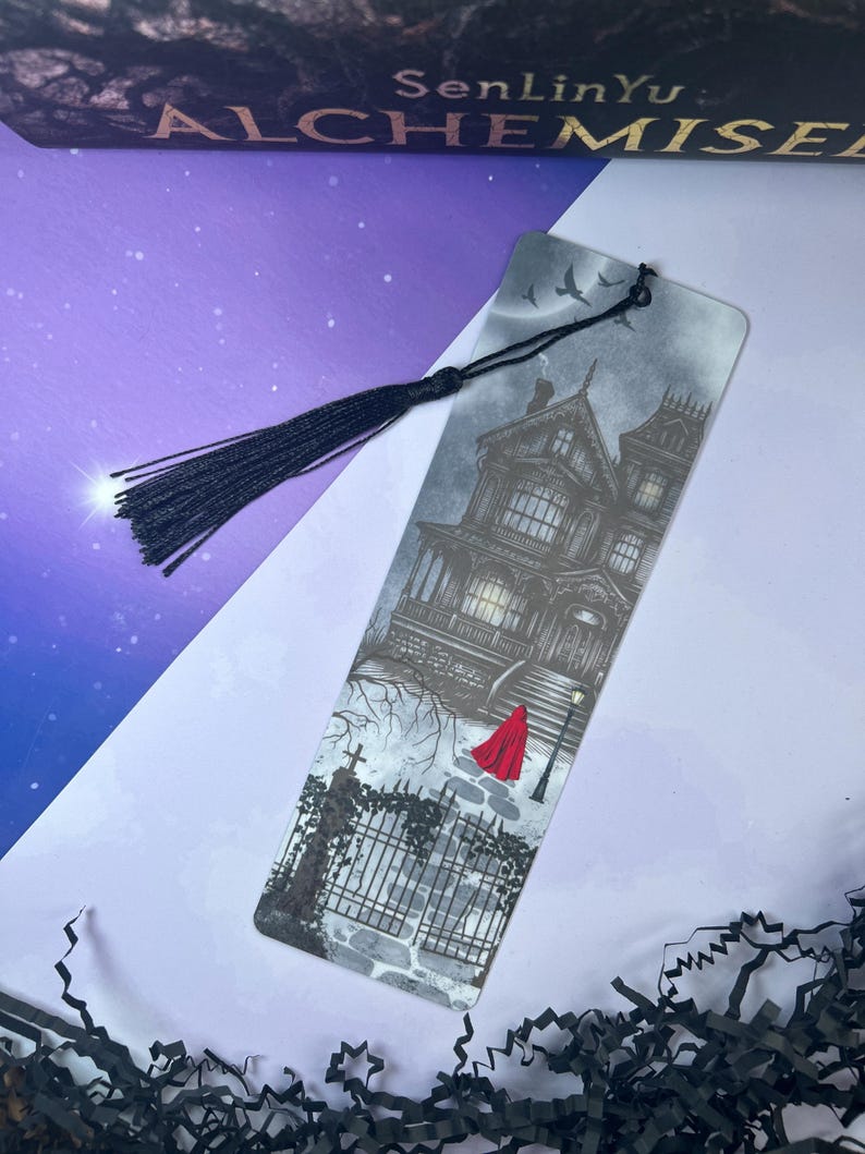 May include: A bookmark featuring a detailed illustration of a haunted house with a red-cloaked figure. The bookmark has a black tassel and the text "SenLinYu: Alchemise" at the top. The artwork is in shades of gray and black.