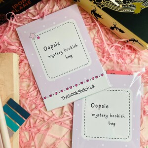 May include: Two purple cards with white polka dots and white text that reads "Oopsie mystery bookish bag" and "ThebookShack.uk".