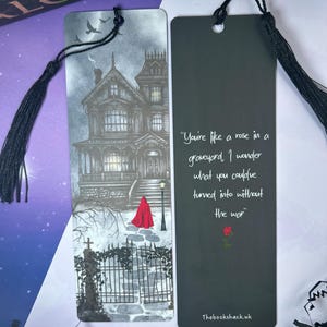 May include: Two bookmarks with black tassels. One features a grayscale illustration of a haunted house and a figure in a red cloak. The other has a quote about a rose and a graveyard, with a rose graphic and the text "Thebookshack.uk".