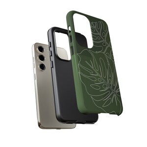 May include: A green phone case with a white outline of tropical leaves. The case is shown with a black phone case and a gold phone.