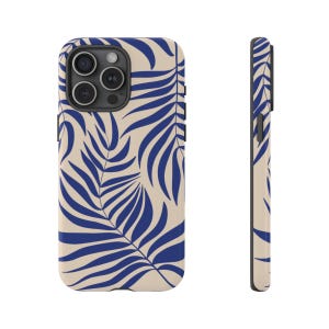 May include: A beige phone case with a blue palm leaf pattern. The case has a cutout for the camera lens.
