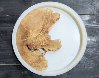 May include: A round, white tray with a natural wood slice embedded in the center. The wood slice has a unique, organic shape and a light brown color.