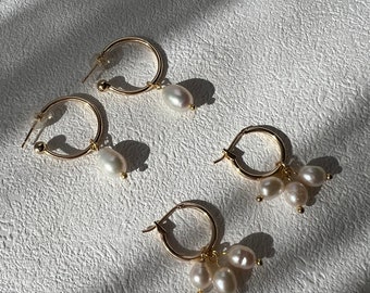 Puede incluir: Tres pares de pendientes de aro de oro con detalles de perlas. Los pendientes presentan una perla colgante única, un grupo de tres perlas y un grupo de cuatro perlas.