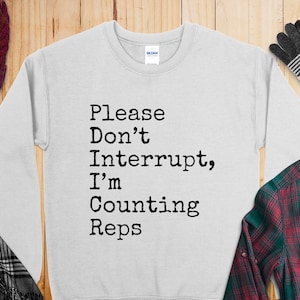 May include: A gray sweatshirt with the text "Please Don't Interrupt, I'm Counting Reps" printed in black.