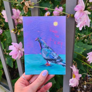 Könnte beinhalten: Ein Gemälde eines Taubens mit einem lila und blauen Hintergrund. Die Taube blickt nach rechts und der Text "CHASE THE LIGHT" ist in rosa Buchstaben über der Taube geschrieben.
