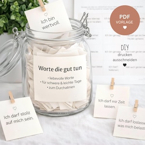 Puede incluir: Un tarro de cristal transparente lleno de pequeñas notas blancas, algunas sujetas con pinzas de madera. El tarro tiene un cierre metálico y está etiquetado con texto en alemán. Se ven notas adicionales con texto en alemán, junto con un círculo marrón con el texto "PDF Vorlage".
