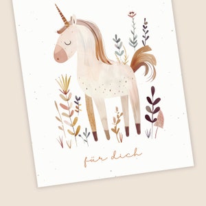 May include: A white unicorn with a brown mane and tail stands in a field of brown, pink, and green wildflowers. The unicorn has closed eyes and a small horn. The text "f&uuml;r dich" is written below the unicorn.