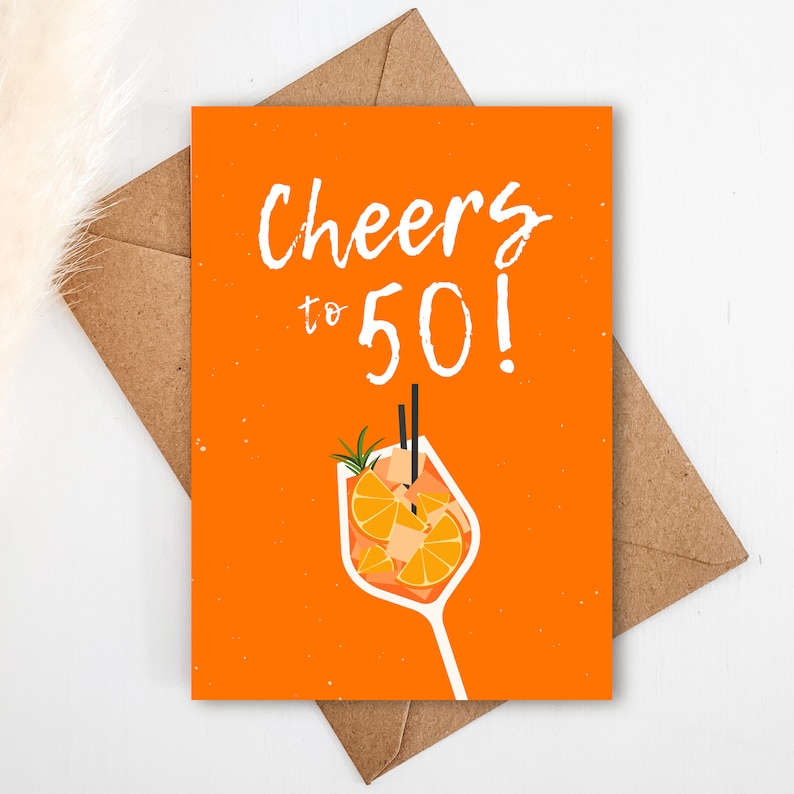 May include: Orange card with the text "Cheers to 50!" in white. A white outline of a glass with orange slices and a sprig of rosemary is below the text.