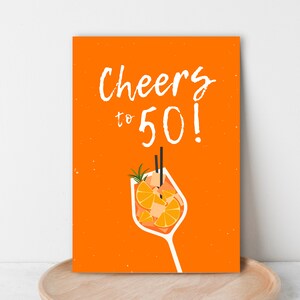 May include: Orange card with the text "Cheers to 50!" in white. An orange drink with a slice of orange and a sprig of rosemary is pictured below the text.