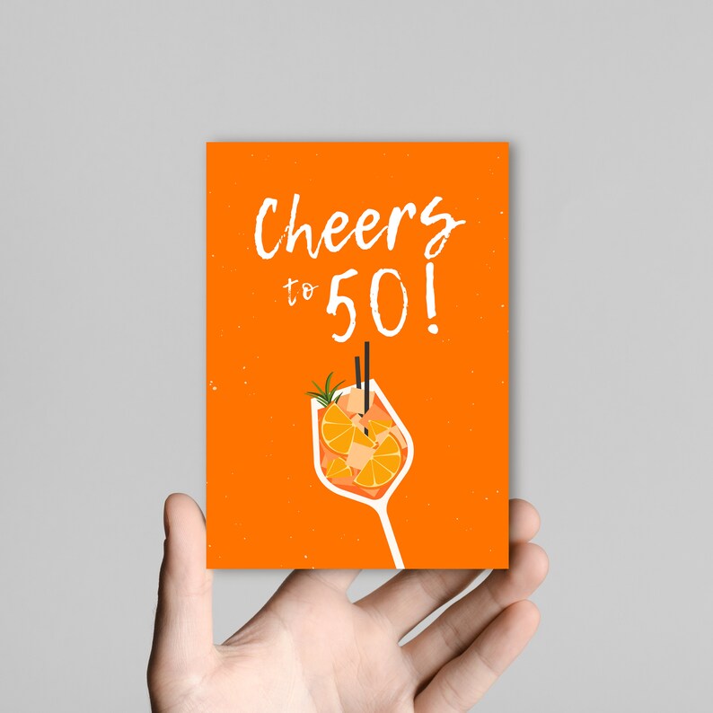 May include: Orange card with the text "Cheers to 50!" in white. A cartoon illustration of a glass of orange juice with two straws is in the bottom center of the card.