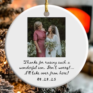 May include: White ceramic ornament with a gold string for hanging. The ornament features a photo of two women and text that reads, "Thanks for raising such a wonderful son. Don't worry!... I'll take over from here! 08.28.25". The word "CUSTOMIZED" is in the upper right corner.