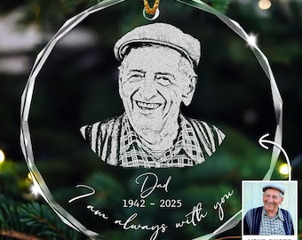 May include: A clear, round, personalized Christmas ornament with a photo of a smiling man wearing a cap. The ornament has the text "Dad 1942-2025 I am always with you." A small photo is in the lower right corner.