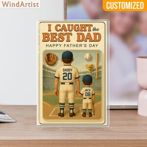 May include: A personalized Father's Day gift featuring a baseball theme. The image shows a father and son in baseball uniforms, with the text "I CAUGHT the BEST DAD" and "HAPPY FATHER'S DAY". Includes baseball, bat, glove, and trophy.