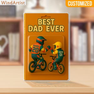 May include: A customized gift package with the text "BEST DAD EVER." The package features two figures on bicycles, one labeled "DADDY 20" and the other "DAVID 01." The figures are wearing helmets and colorful cycling gear. The package is orange and has a clear plastic front.