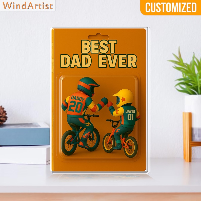 May include: A customized gift featuring two figures on bicycles bumping fists, with the text "BEST DAD EVER." The figures wear helmets and jerseys with the names "DADDY" and "DAVID" and the numbers 20 and 01. The background is orange.