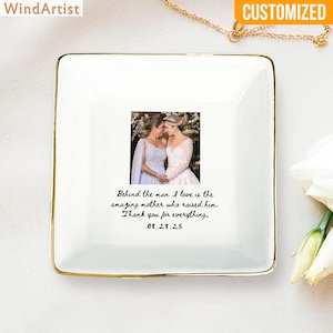 May include: A square, white ceramic trinket dish with a gold rim. The dish features a photo of two women in wedding dresses. Text on the dish reads: "Behind the man I love is the amazing mother who raised him. Thank you for everything, 08.28.25."