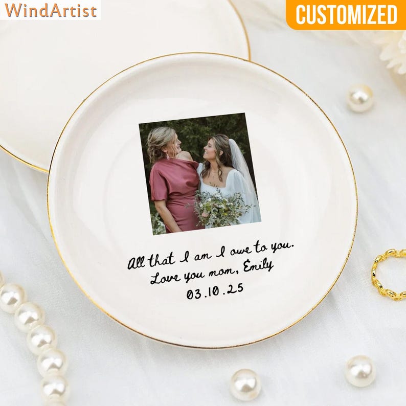 May include: A white ceramic mug with a black handle and the text "But First, Coffee" in a handwritten style. The mug is on a white surface. The mug is approximately 4 inches tall.